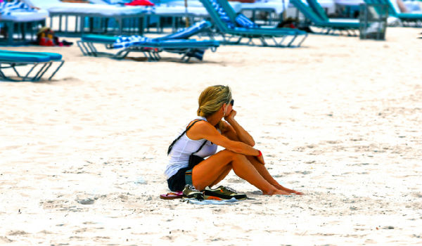 Frau sitzt alleine am Strand