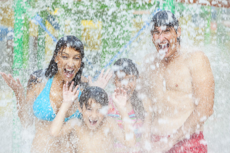 Familie steht unter einer Riesendusche in einem Wasserpark